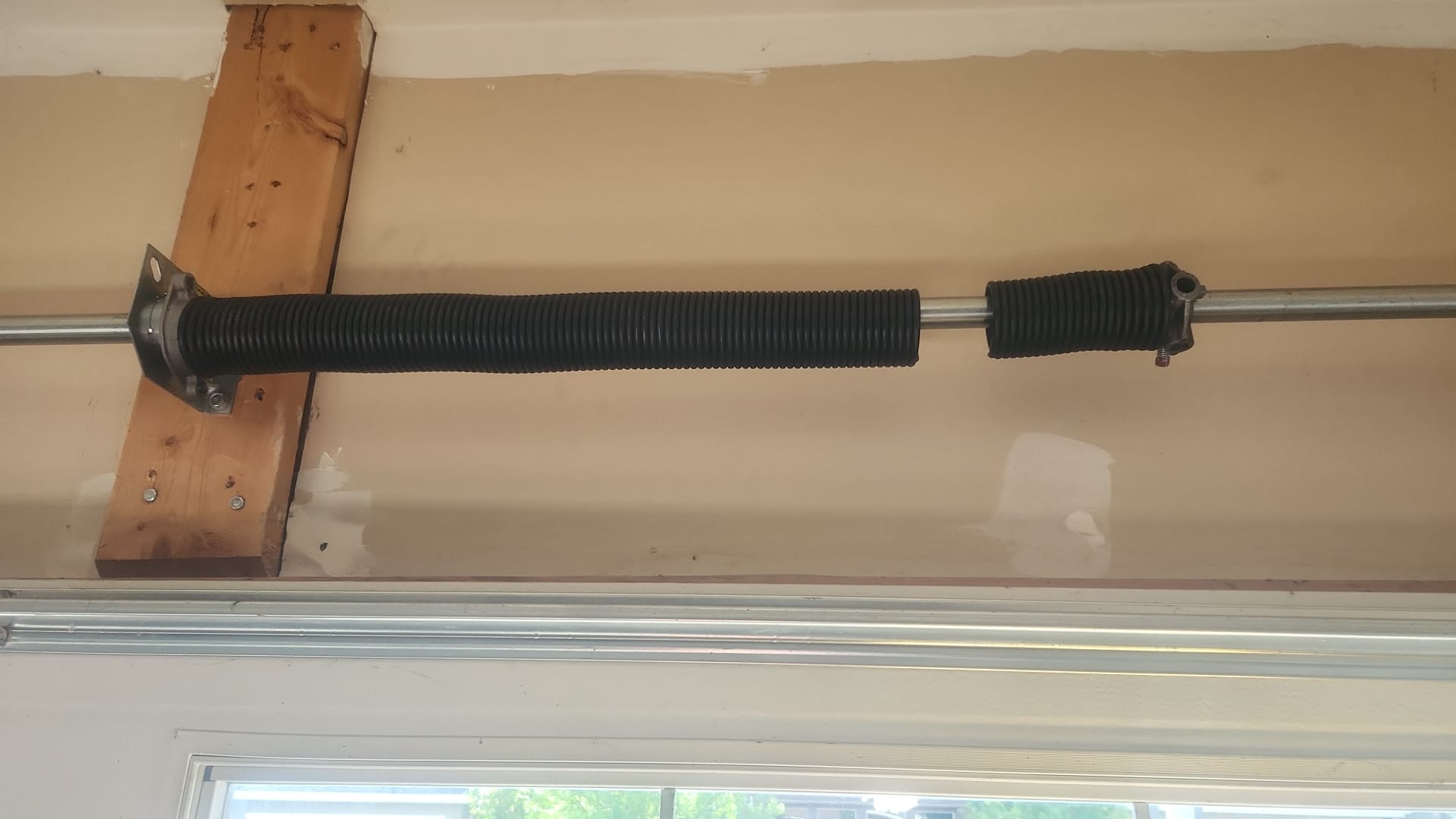 Broken garage door torsion spring separated around the metal shaft