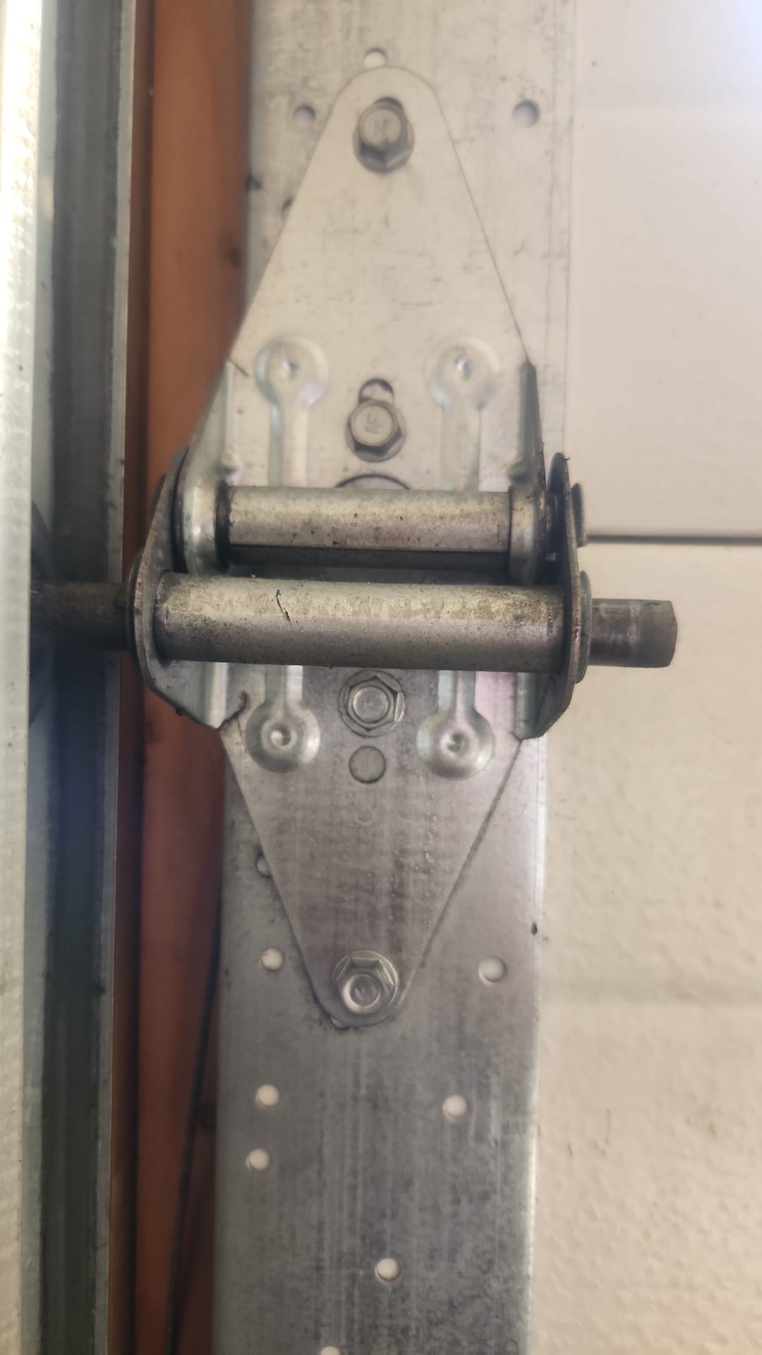 Close-up of worn roller and hinge hardware beside a garage door track