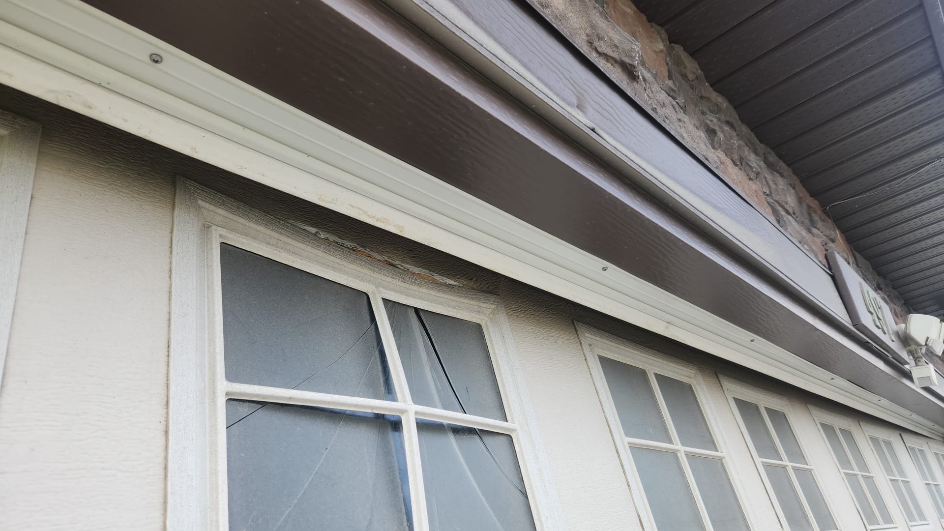 Cracked and bowed upper panel on a white garage door with windows