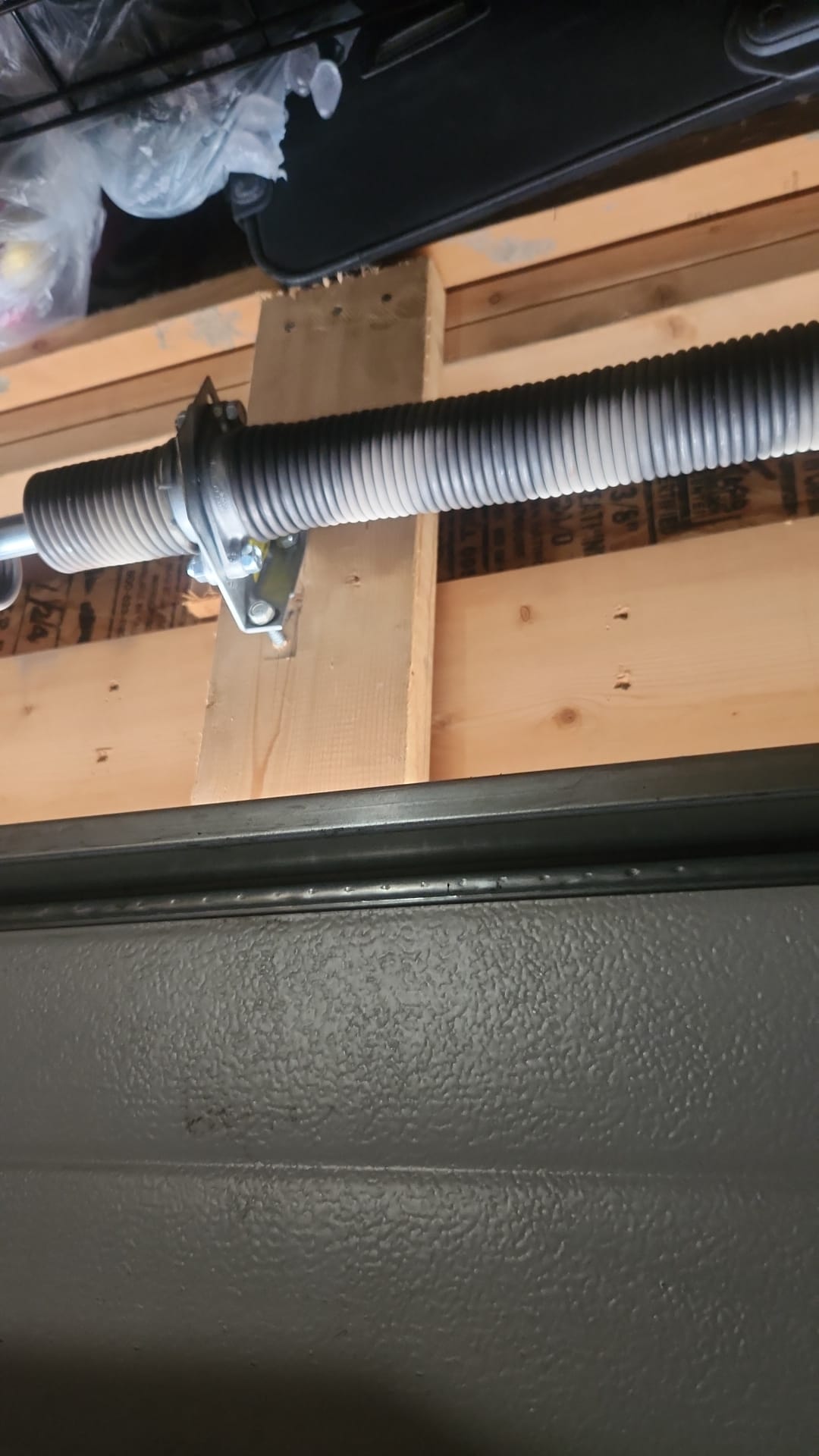 Close-up of a garage door torsion spring mounted above the door